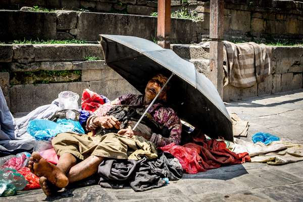 An old woman tries to sleep in the sun in Kathmandu, Nepal