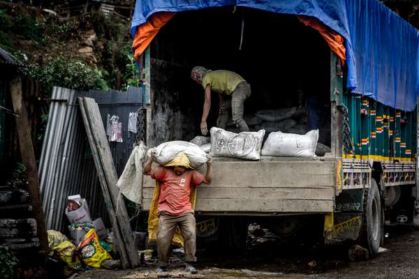 A man unloads rice from a lorry in a village, Nepal